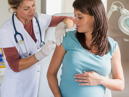 врач делает беременной девушке прививку