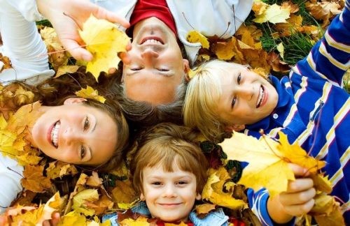 родители с детьми лежат в осенней листве