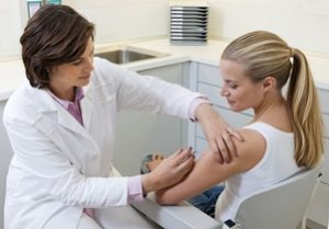 доктор делает прививку женщине в поликлинике