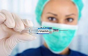 медсестра держит шприц с надписью «грипп»