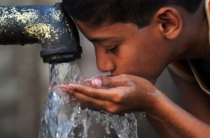 мальчик пьёт воду из под колонки