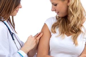 врач делает девушке прививку в руку