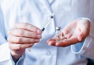 вакцина и шприц в руках у врача